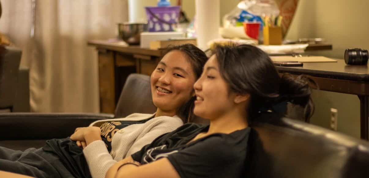 Two friends laughing together on a couch